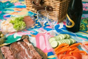 A selection of food and wine next to a picnic basket